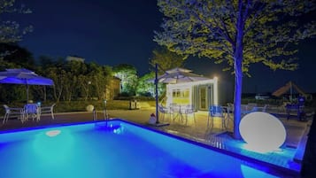An outdoor swimming pool area with lounge chairs and a small gazebo.