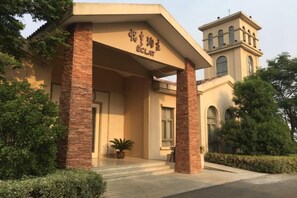 A building with a covered entrance, a tower-like structure, and a potted plant in front. - Eclat (Xuyi)