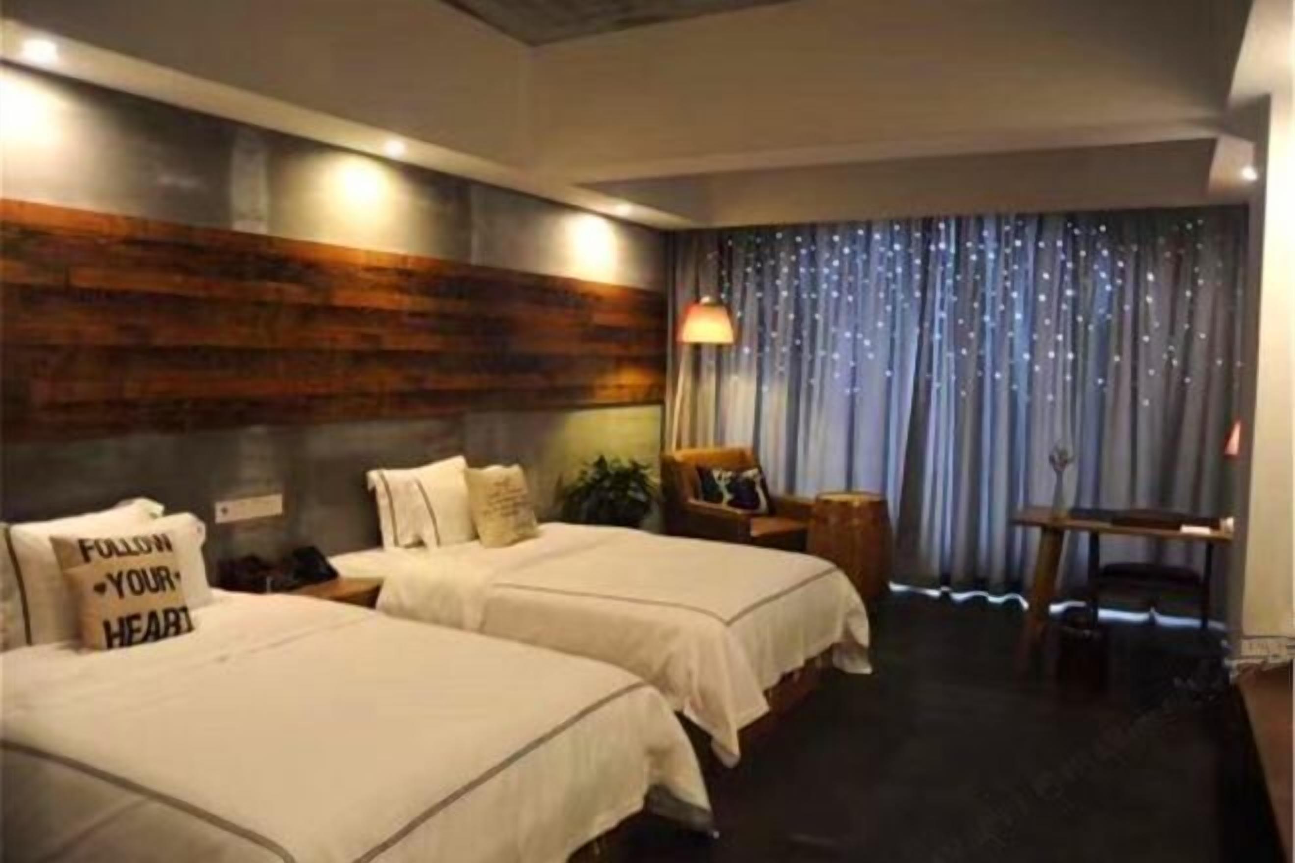 A hotel room with two beds, a desk, a chair, a nightstand, and a curtain with a starry pattern.