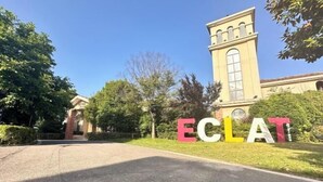 A building with a large sign reading 'ECLAT' in front of a paved driveway. - Eclat (Xuyi)