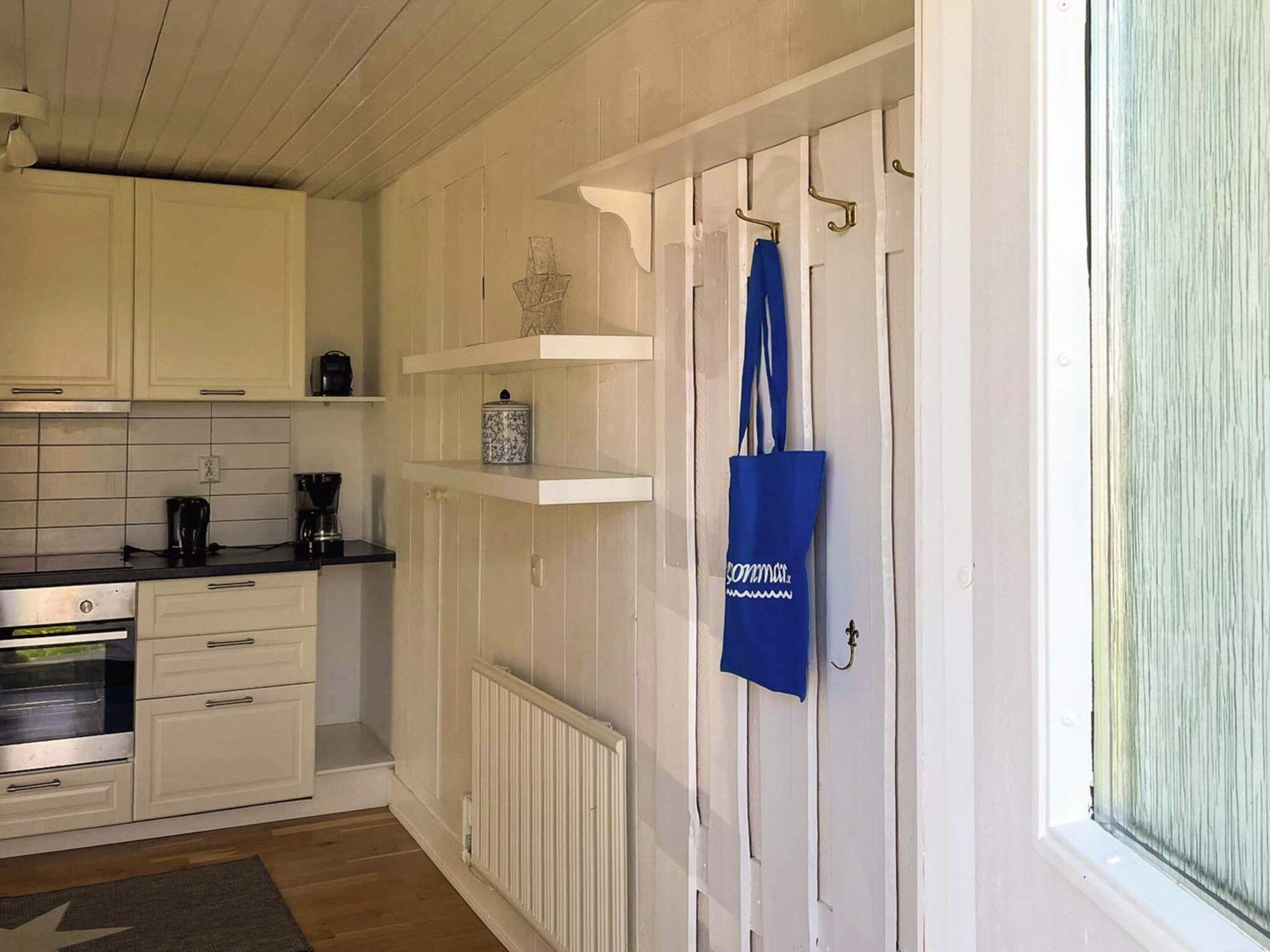 A kitchen with white cabinets, a coffee maker, and a blue tote bag hanging on a door.