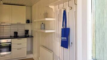 A kitchen with white cabinets, a coffee maker, and a blue tote bag hanging on a door.