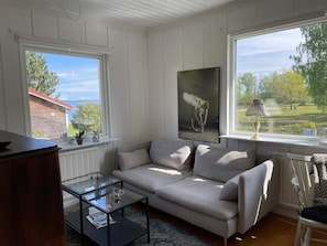 A living room with a sofa, a glass coffee table, a painting, and a view of the outdoors. - 5 Star Holiday Home in Vingaker (Vingåker)
