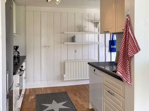 A kitchen with white cabinetry, a black countertop, a star-patterned rug, and a blue bag hanging on the wall.