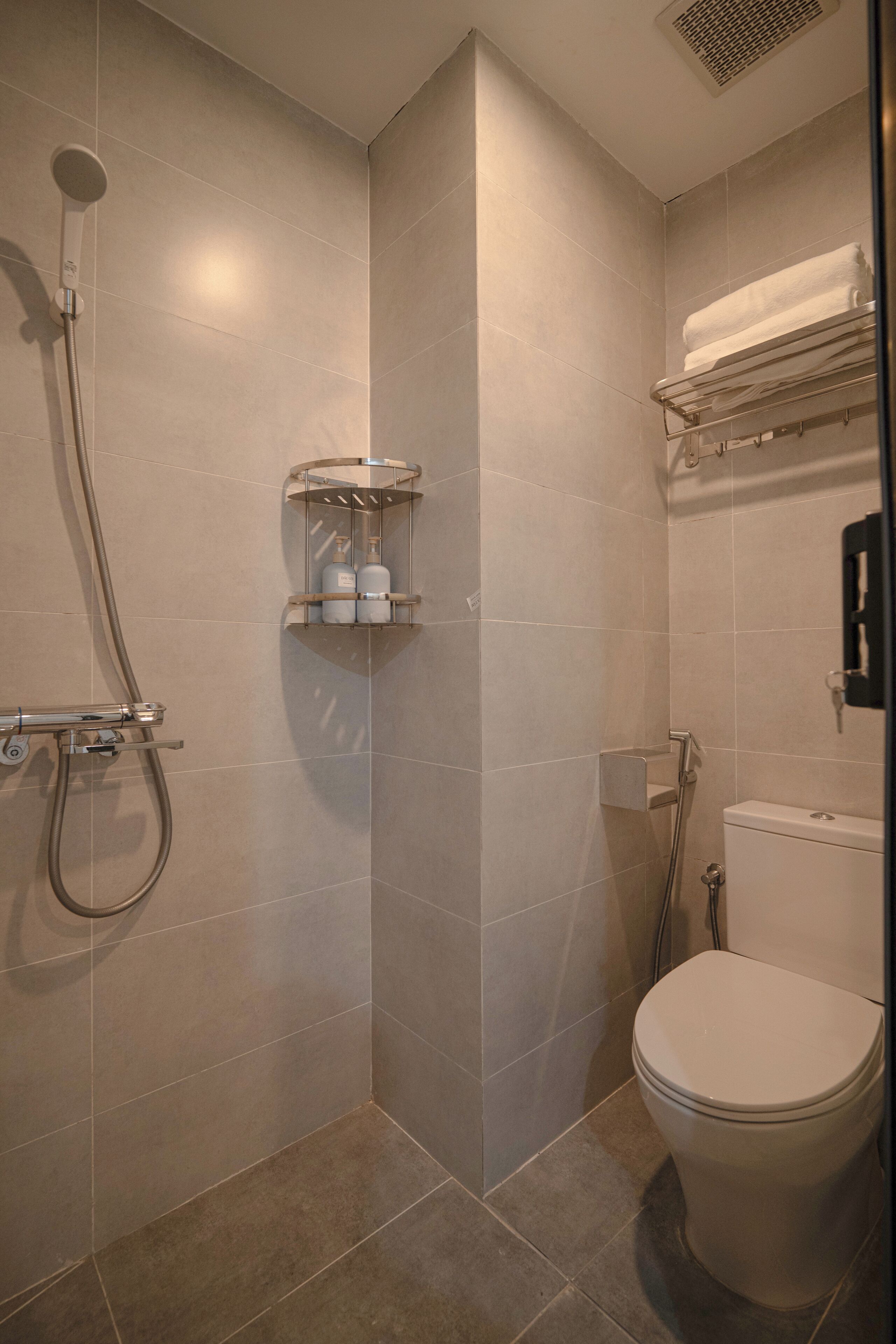 Un baño con ducha, inodoro y perchero para toallas.