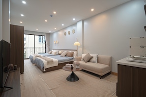 Una habitación de hotel moderna con cama, sofá, mesa de centro y televisión.