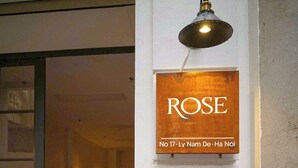 Een gang met een bord waarop staat 'ROSE No 17 - Ly Nam De - Ha Noi' en een lamp erboven.