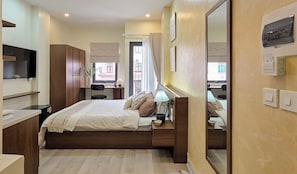 Un dormitorio con cama, mesita de noche, lámpara y espejo.
