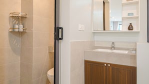 Een moderne badkamer met een douchecabine van glas, een houten wastafelmeubel en een spiegel boven de wastafel.