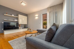 Ein modernes Wohnzimmer mit grauem Sofa, einem Holztisch, einem Flachbildfernseher und einer eingebauten Regaleinheit.