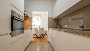 Una cuina moderna amb armaris blancs, forn d'acer inoxidable i taulell de fusta.