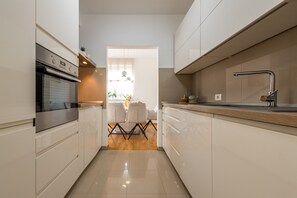 Eine moderne Küche mit weißen Schränken, einem Edelstahlbackofen und einer Holz Arbeitsplatte.
