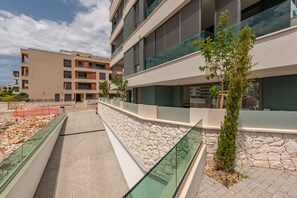A modern building with multiple floors, stone walls, and glass railings. - Zaria Luxury Residence (Zadar)