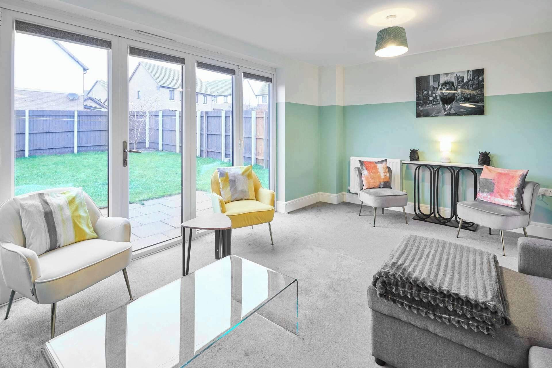 A modern living room with a glass coffee table, two sofas, a small round table, and a radiator.