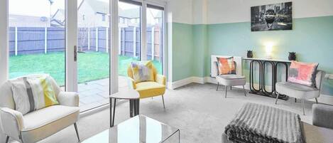 A modern living room with a glass coffee table, two sofas, a small round table, and a radiator.