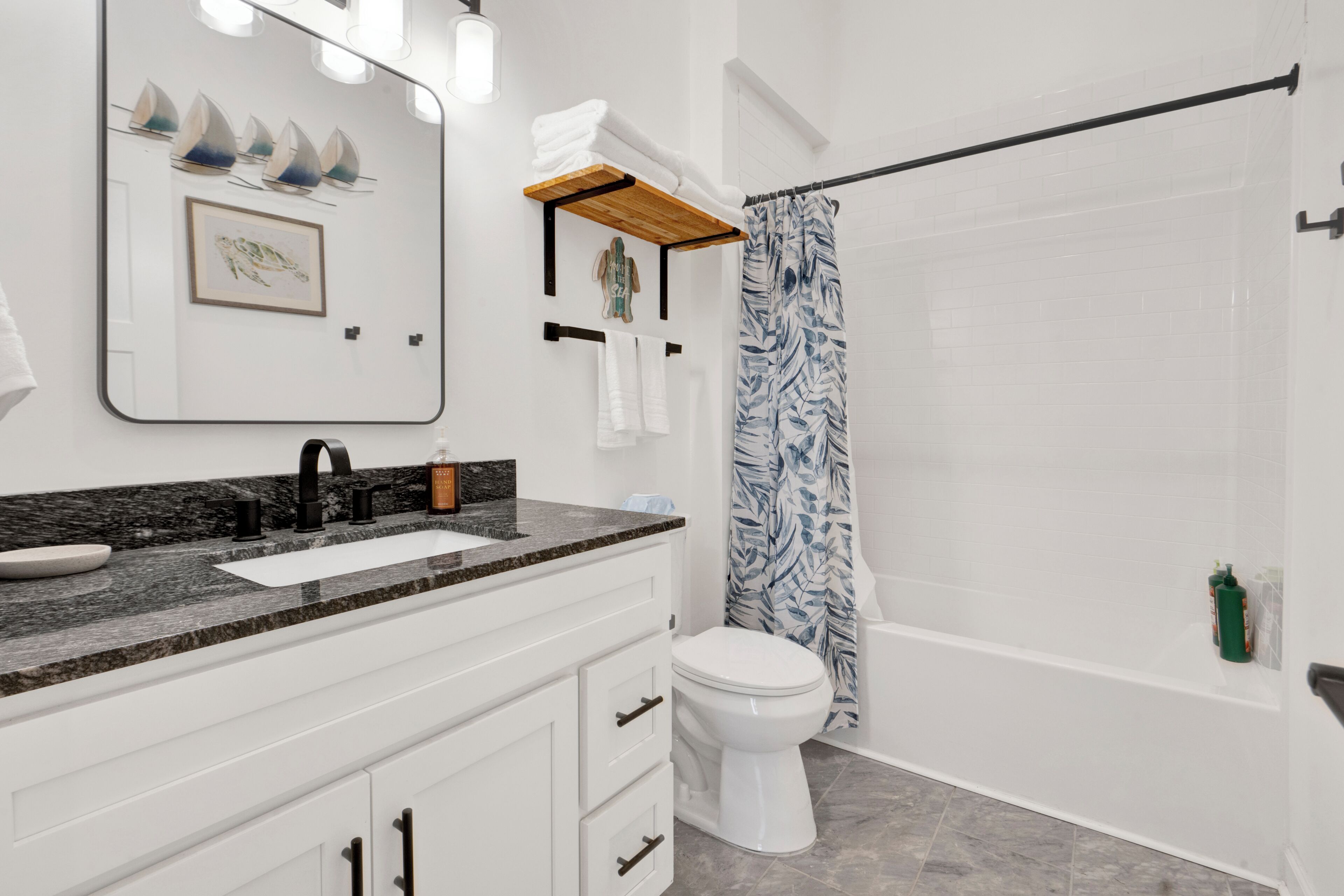 Un baño con lavamanos blanco, espejo, inodoro y cortina de ducha.