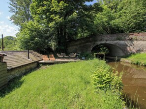 A stone bridge over a canal with a grassy area and chairs. - The Lime Kiln Keepers Cottage (Ellesmere)