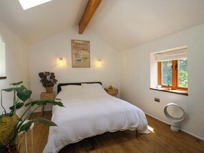 Un dormitorio con cama, lámparas de noche, ventana con vistas, ventilador de techo y un cuadro en la pared.