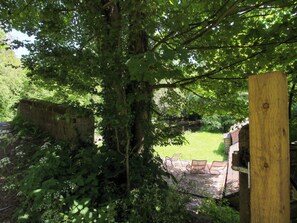 Ein rustikaler Außenbereich mit Holzzaun, Steinmauer und einer grünen Wiese.