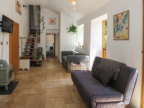Una sala de estar con sofá, televisión, escalera y comedor.