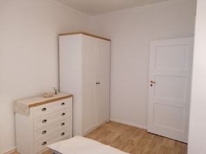 Ein Schlafzimmer mit einem weißen Kleiderschrank, einem Nachttisch und einer Tür.