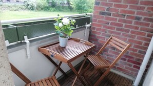 A wooden deck with a table and two chairs, a potted plant, and a brick wall. - Vacation rental near Jungfernheidepark with free parking (Berlin)