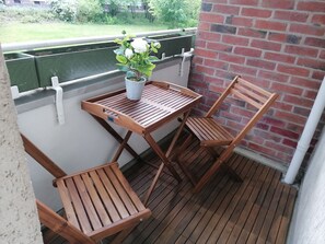 Eine Holterrasse mit Tisch, zwei Stühlen, einem Topfpflanzen und einer Ziegelwand.