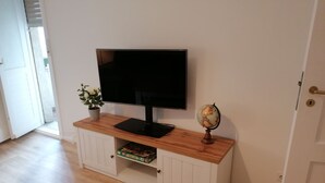 A room with a flat-screen TV on a wooden cabinet, a globe, and a plant. - Vacation rental near Jungfernheidepark with free parking (Berlin)