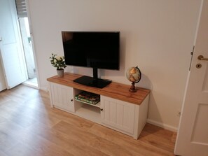 Ein Zimmer mit Flachbildfernseher auf einer Holzkabine, einem Globus und einer Pflanze.