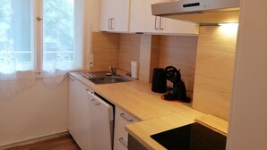 A compact kitchen with white cabinets, a stainless steel sink, a black coffee maker, and a built-in stove. - Vacation rental near Jungfernheidepark with free parking (Berlin)
