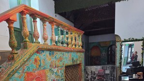 Eine Treppe mit farbenfrohen, verzierten Geländern und einer gemusterten Wand.