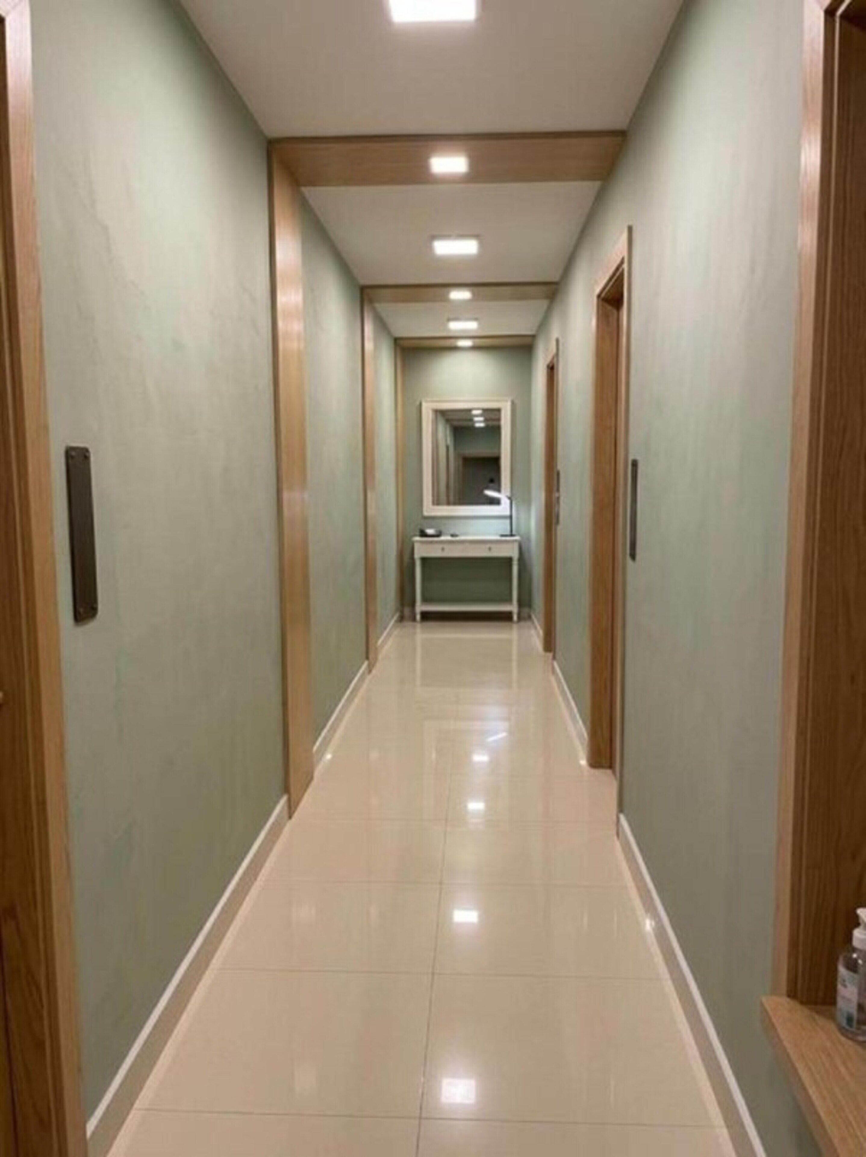A hotel hallway with a mirror, a bench, and a door on the right.
