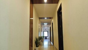 A hallway with a tiled floor, potted plants, and a door at the end. - Hotel Lotus Inn Near By OTABoostup (Chandigarh)