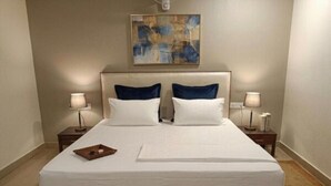 A neatly made bed with white linens, two pillows, and a small tray on the left side. - Hotel Lotus Inn Near By OTABoostup (Chandigarh)