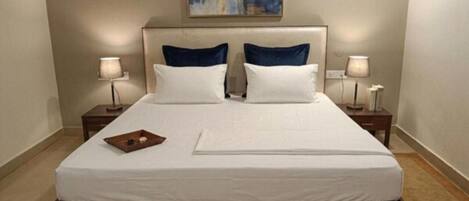 A neatly made bed with white linens, two pillows, and a small tray on the left side.