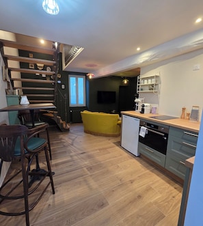 Une cuisine moderne avec un coin repas, un plancher en bois et un escalier.