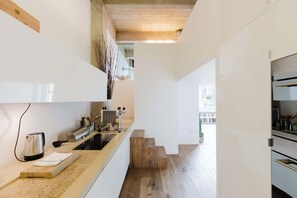 A modern kitchen with a wooden staircase, a kettle, and a coffee machine. - Sunny 1BD Loft Style Flat in the Heart of Hackney (London)
