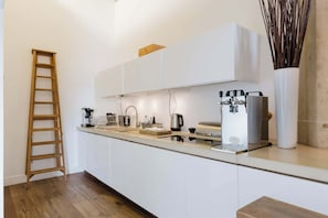 A modern kitchen with white cabinets, a stainless steel range hood, a coffee machine, and a kettle. - Sunny 1BD Loft Style Flat in the Heart of Hackney (London)