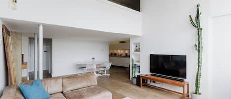 A modern living room with a sofa, coffee table, and a flat-screen TV.
