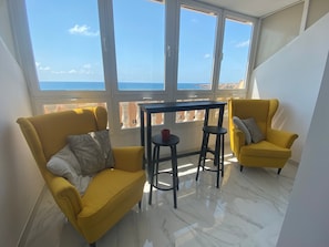 A room with two yellow chairs, a small table, and large windows offering a view of the sea. - Studio Apartment 'Sea Breeze' with Sea View, Wi-Fi and Air Conditioning (Torrevieja)