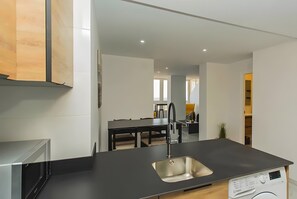 A modern kitchen with a built-in dishwasher, a stainless steel sink, and a dining area with a dark wooden table and chairs. - Studio Apartment 'Sea Breeze' with Sea View, Wi-Fi and Air Conditioning (Torrevieja)
