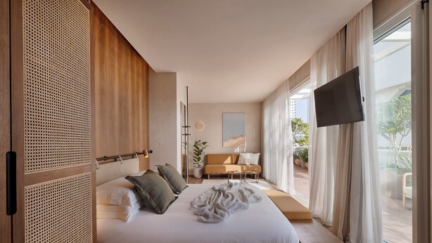 A modern bedroom with a large bed, a sofa, a TV, and a balcony with a view. - The ABY Hotel  (Tel Aviv)