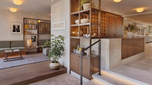 A modern interior with a central staircase, wooden shelving, and a seating area with a sofa and coffee table. - The ABY Hotel  (Tel Aviv)
