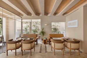 Una sala de estar moderna con un sofá, sillas, una mesa de centro y una planta.