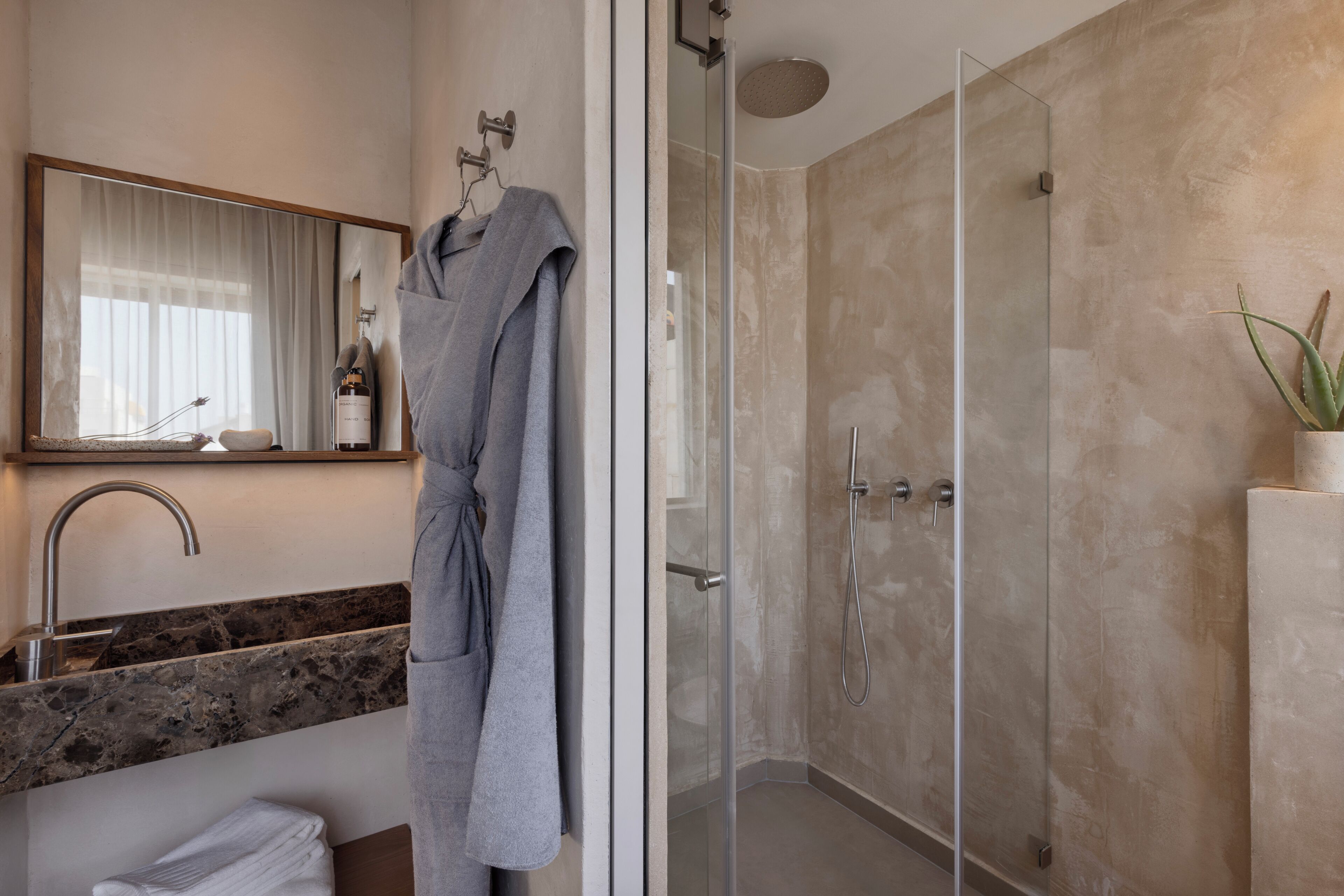 A modern bathroom with a glass-enclosed shower, a marble countertop, and a large mirror.