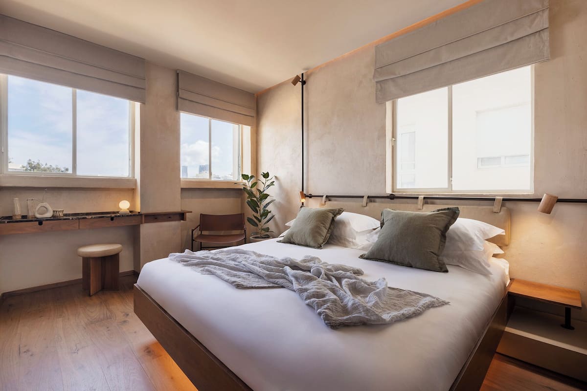 A modern bedroom with a large bed, bedside tables, a desk, and a chair.