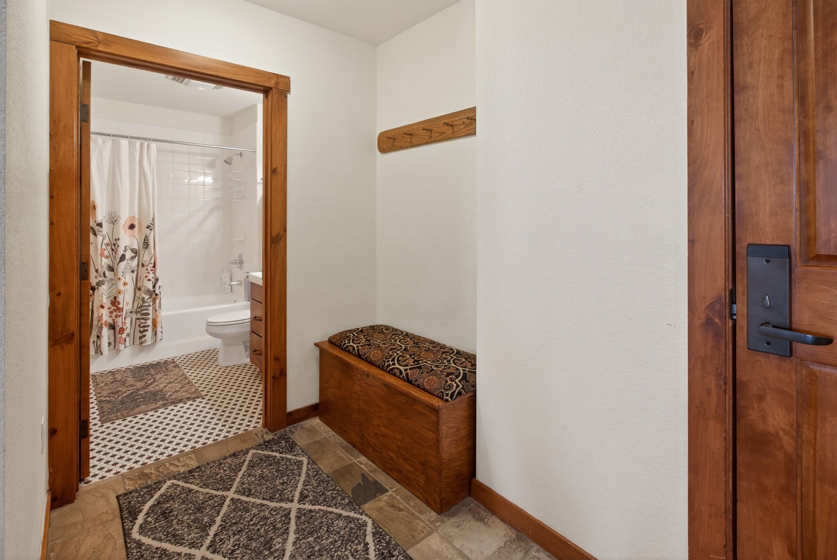 A bathroom with a shower, toilet, and a bench.