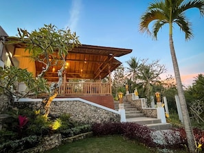 A modern house with a wooden deck, stone steps, and tropical plants. - Griyatama Bungalow (Penida Island)
