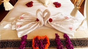 Una cama con dosel, almohadas y un adorno con forma de corazón hecho de flores.