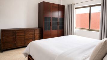 A bedroom with a bed, a wardrobe, and a window with curtains.
